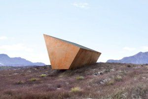 Върху черна равнина заобиколена от стръмни планини стои гигантска стоманена