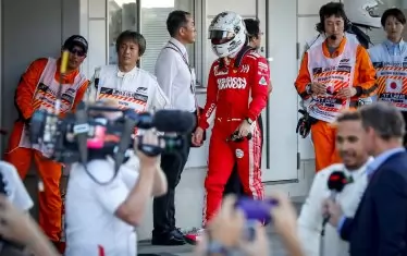 Разочарованият от шестото си място Себастиан Фетел се прибира с наведена глава към бокса, докато победителят в Япония Люис Хамилтън (на преден план) дава усмихнат първото си интервю след състезанието.