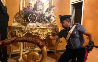  Италиански полицай претърсва жилището на заловен мафиот. В Италия Законът за гражданската конфискация се използва главно за борба с мафията.