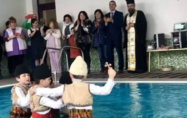  На Йордановден в контролираната среда на закрития басейн дечица в носии вадят кръста и играят хоро под умилените погледи на педагогическото ръководство, районния кмет и представители на БПЦ. Лагерите веднага се консолидират – „консерваторите“ (патриотите, националистите) са трогнати и хвалят усилието да се пазят традициите живи; а пък „либералите“ (космополитите, гражданите на света, надарени да разбират неговата култура) скачат в защита на цивилизацията и добрия вкус.