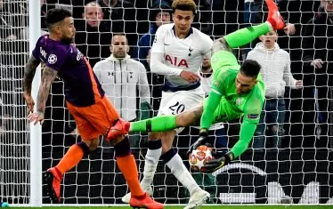 Вратарят на "Манчестър С" Едерсон пада, но с топка в ръце, след като е успял да изпревари халфа на "Тотнъм" Деле Али (в средата) по време на 1/4-финала на "Хотспър Стейдиъм" в Лондон.