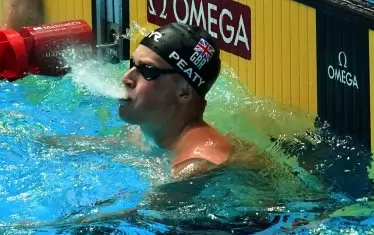 Адам Пийти изстрелва вода от устата си, след като е видял таблото, показващо, че е първият човек, плувал 100 м бруст под 57 секунди.