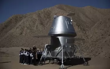 Китайски ученици разглеждат реплика на марсоход, който е изложен в база за подготовка за пътуване на Марс в пустинята Гоби в град Цзинчан, провинция Гансу.
