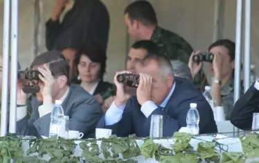 Премиерът Бойко Борисов гледа с бинокъл как военните си играят. 