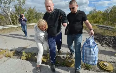 Представители на властите в Киев помагат на бивш украински военнопленник да прескочи мини по време на обмяната на пленници с ДНР в селцето Шчастие в Източна Украйна.