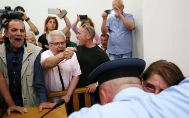 Полицай охранява нотариус на търг за продажба на имоти заради неплатени банкови кредити през 2017 г. в Атина.