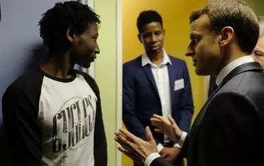  Еманюел Макрон разговаря с мигрант от Судан в мигрантски център в Северна Франция.