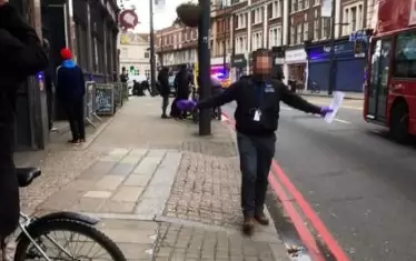  Полицай приканва хората да се отдръпнат, докато в дъното мединиски екипи оказват първа помощ на ранените