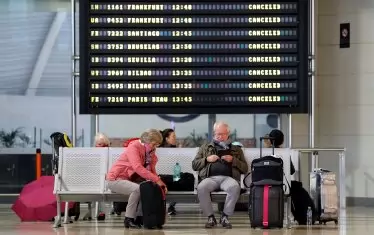 Пътници почиват под информационен панел, който показва всички отменени полети на летище Манисес във Валенсия. Испания е изправена пред 13-ти пореден ден на национална карантина в опит да забави разпространението на пандемичната болест COVID-19, причинена от Коронавирус SARS-CoV-2. 