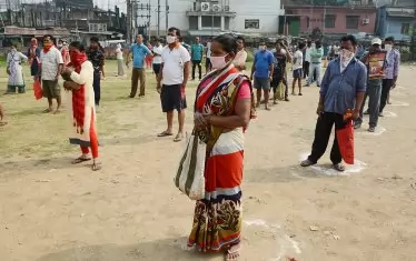 Хората чакат в маркираните кръгове, за да закупят зеленчуци, доставени от Службата за  снабдяване с храна по време на националната карантина в Асам, Индия.