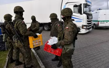  Полски войници раздават храна и вода на чакащите дни наред камиони и коли да преминат границите. 