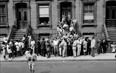 Дизи Гилеспи пресича улицата с фотоапарат за да направи сам няколко снимки на колегите си.