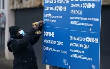 За сравнение - работник поставя информационна табела пред подобен център за ваксиниране срещу COVID-19 в Монреал, като за целта е отделена цяла болница.