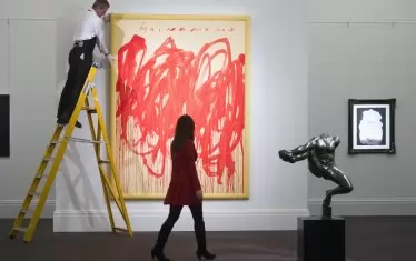 Служител на „Сотбис“ `s застава на стълба, коригирай картина на Туомбли, озаглавена „Без име“, преди търг на аукционната аукционната къща в Лондон, през  2016 г. Картината се оценява на 20-30 милиона долара. 