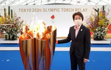 Шефът на организационния комитет Сейко Хашимото позира до олимпийския огън.