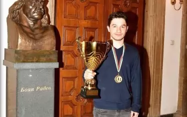Шампионът Мартин Петров позира с шампионския трофей пред бюста на родения в Перник легендарен български борец Боян Радев.