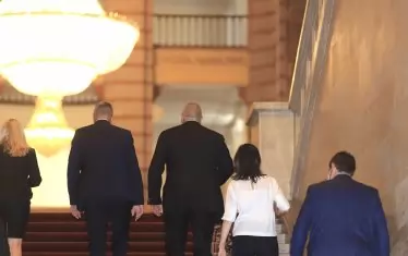  Фоторепортерите успяха да уловят само в гръб как Бойко Борисов отвежда Стефан Янев към залата, в която се проведе церемонията по предаването.