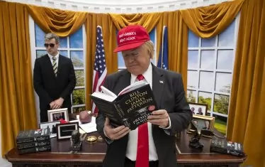 Това не е Доналд Тръмп, който чете предишния роман на Клинтън и Патерсън на работното си място, а актьор сред декор, инсталиран на лондонската гара Ватерло през 2018 г., като реклама за „Президентът изчезна“. 