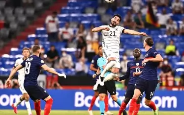 Атакуващият халф на Германия Илкай Гюндоган се е извисил, за да отиграе топката с глава, пред погледа на трима французи - Карим Бензема (№19), Нголо Канте (№13) и Адриан Рабио (№14).