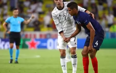 Германският нападател Кай Хаверц помага на френския бранител Рафаел Варан да се изправи след остро единоборство помежду им.