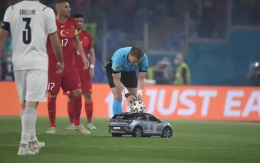 Главният рефер Дани Макели се навежда преди началото на мача да вземе топката, която бе докарана до центъра на терена от рекламна кола с дистанционно управление.