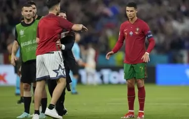 Допускането на публика по стадионите по време на Евро 2020 върна и позабравените спомени за нахлуващи зрители на терена, както в случая с този фен в Будапеща, който се опитва да покаже колко е прехласнат по Кристиано Роналдо.