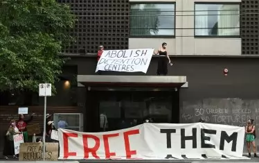 "Премахнете центровете за задържане" и "Освободете ги всички" пише на два от транспарантите, разпънати тази сутрин пред "Парк Хотел" в мелбърнското предградие Карлтън, където е принудително настанен Новак Джокович.