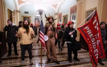 Джейк Анджели (в средата с рогатата шапка) и други поддръжници на Тръмп в Капитолия. Известен като „Шаманът на КюАнон“, вярващият в конспирации вече е сред осъдените.  Присъдата му е 41 месеца затвор. 