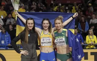 Новата световна шампионка в скока на височина в зала Ярослава Махучих позира щастлива с украинското знаме в компанията на подгласничките си Елинор Патерсън (вдясно) и Надежда Дубовицкая (вляво) след края на състезанието в белградската зала "Щарк Арена".