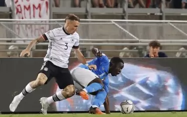 Германският бранител Давид Раум (№3) притиска италианския нападател Вилфрид Гнонто по време на двубоя в Болоня.