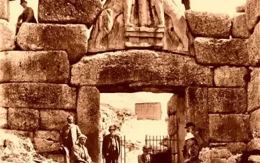 Шлиман на Лъвската порта в Микена. Вратите към древния дворец крепост се "пазят" от два големи каменни лъва. 