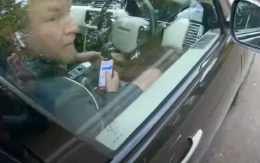 Гай Ричи е заснет от Майк ван Ърп с телефон в ръка. 