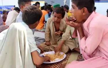   Деца, засегнати от наводненията, чакат помощ в Ларкана, провинция Синд.