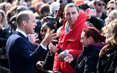 Принц Уилям поздравява хората на опашката.