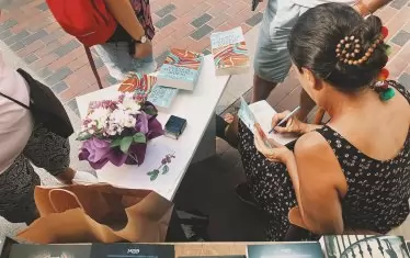 Писателката раздава автографи.