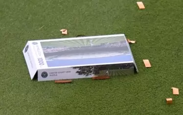 Захвърленият на тревата капак от кутията на пъзела с 1000 парчета, изобразяващ централния корт на "Уимбълдън".