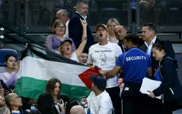 Човек от охраната на "Род Лейвър Арина" подканва протестиращия в подкрепа на Палестина запалянко да напусне трибуните.