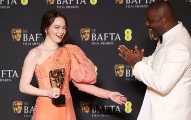 Ема Стоун се радва на статуетката в присъствието на Идрис Елба.