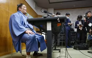 Новият герой на сумото дава пресконференция ден след триумфа си. На снимката се вижда и превързаният му глезен.