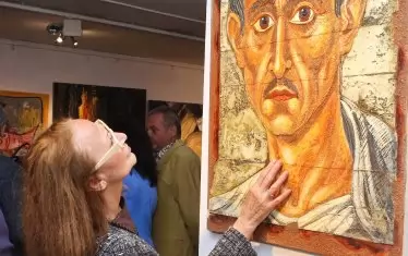  Посетителка с интерес разглежда картините.