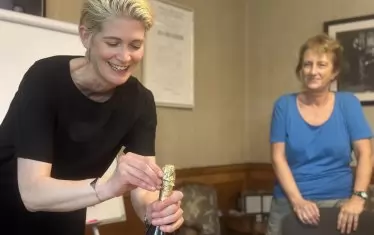  Катрин Медлер отваря шампанското по случай старта на работата по проекта.