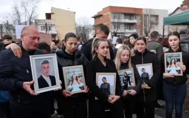 Близки на жертви от дискотеката в Кочани държат техни снимки по време на поклонение в града.