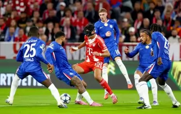 Играещият с маска халф на "Байерн" Александър Павлович се опитва да се промъкне с топката между петима футболисти на "Челси".