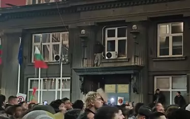 Младеж с вид на футболен фен се е покачил на еркер на сградата до Министерски съвет