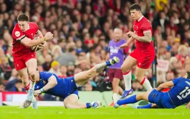 Уелсецът Джош Адамс (вляво) се е откъснал пред играчите на Италия и напредва по време на емоционалния мач в Кардиф.