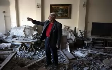   Ранен иранец говори, докато стои в разрушения си апартамент в жилищна сграда, намираща се до синагогата „Хорасаниха“ в Техеран, Иран